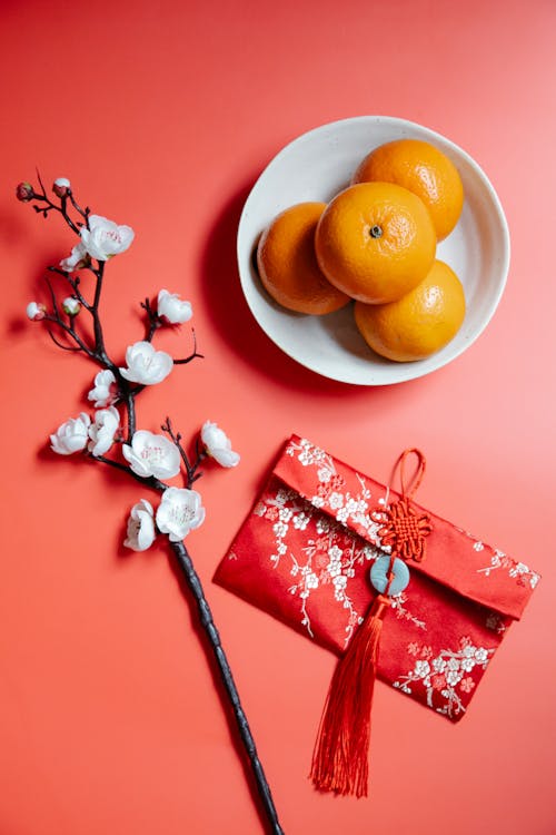 Red packet near blooming Sakura twig and fresh mandarins