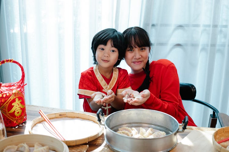 Delighted Ethnic Siblings Smiling And Showing Homemade Chinese Dumplings