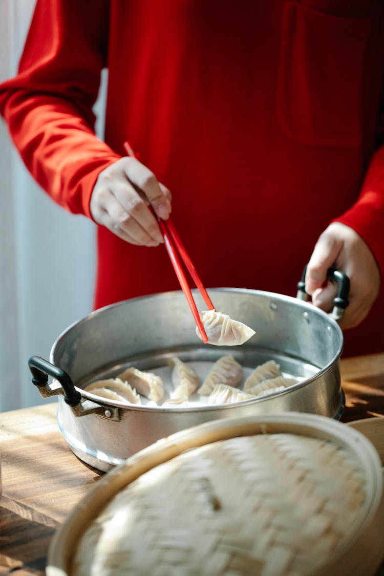 A Person Picking Up A Dumpling Using Chopsticks