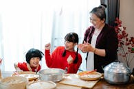 Joyful ethnic grandmother with grandchildren having fun while cooking in kitchen