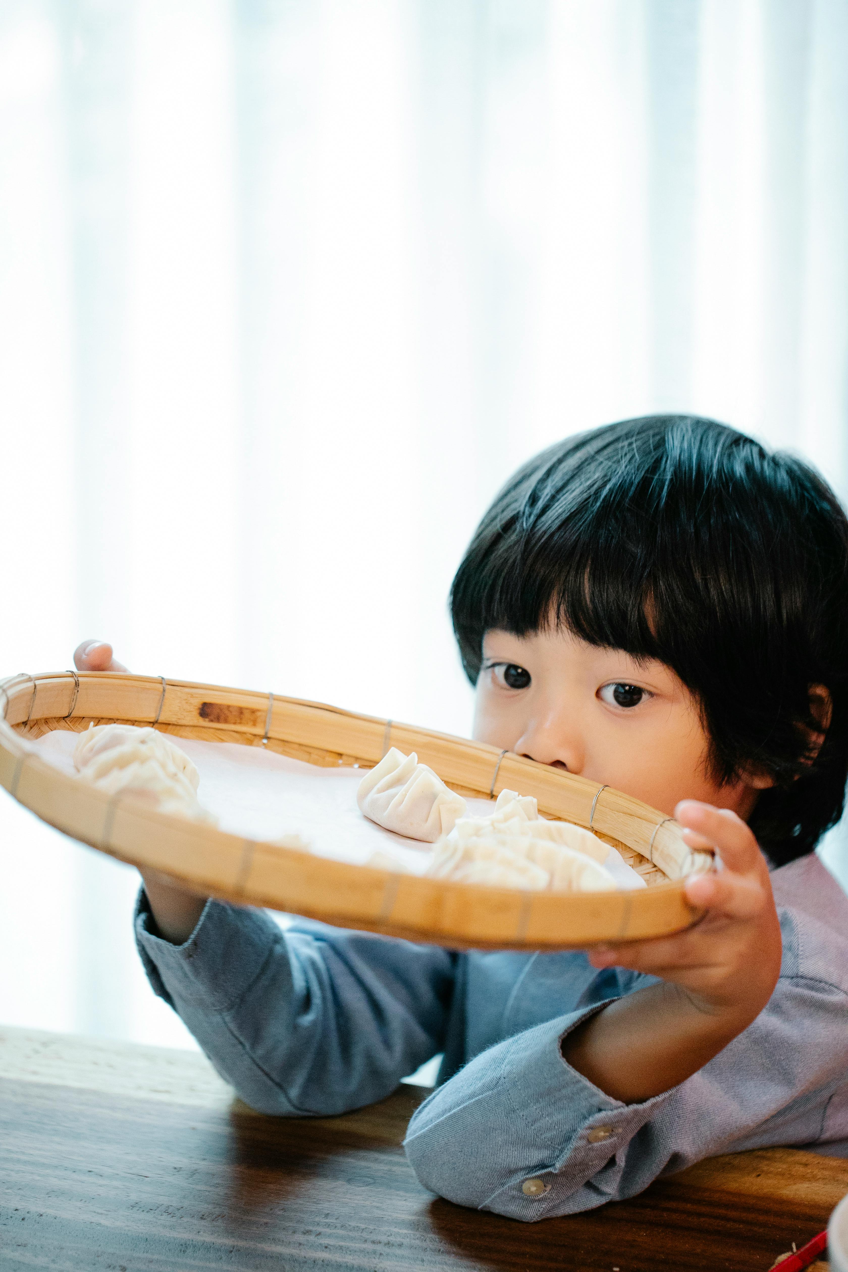 a child holding a tray with dumplings