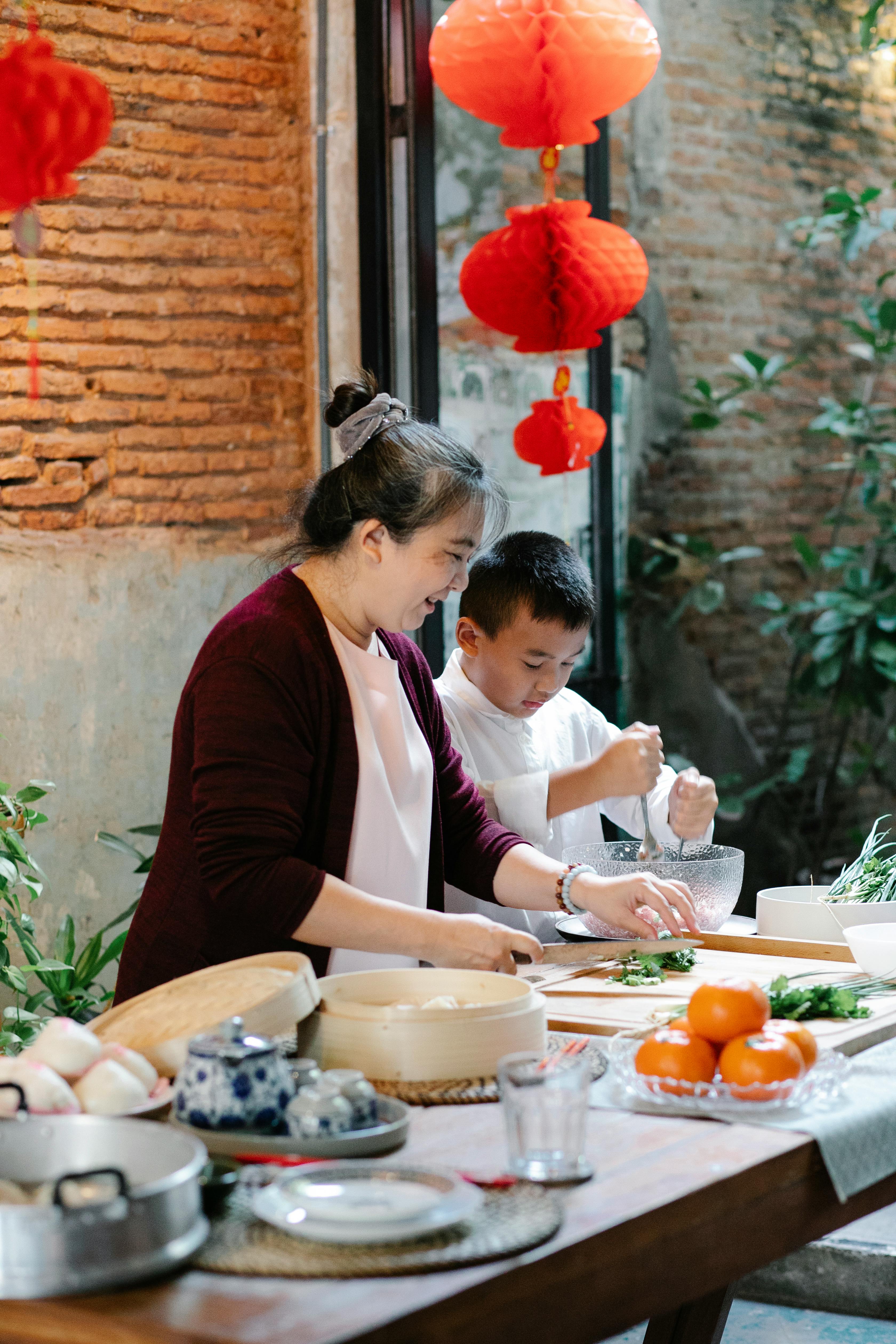 ethnic grandmother with grandson cooking asian dishes in kitchen