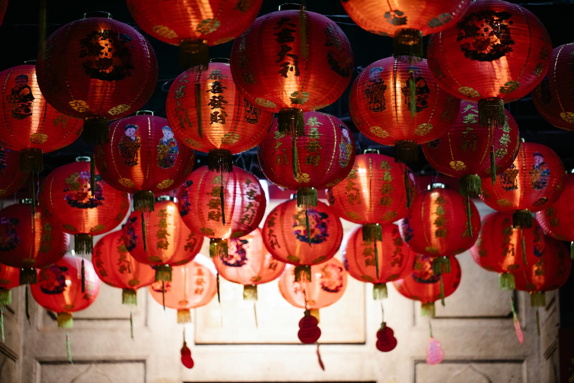 From below of many red rice paper lanterns with golden hieroglyphs hanging on street during celebration of Chinese Spring Festival