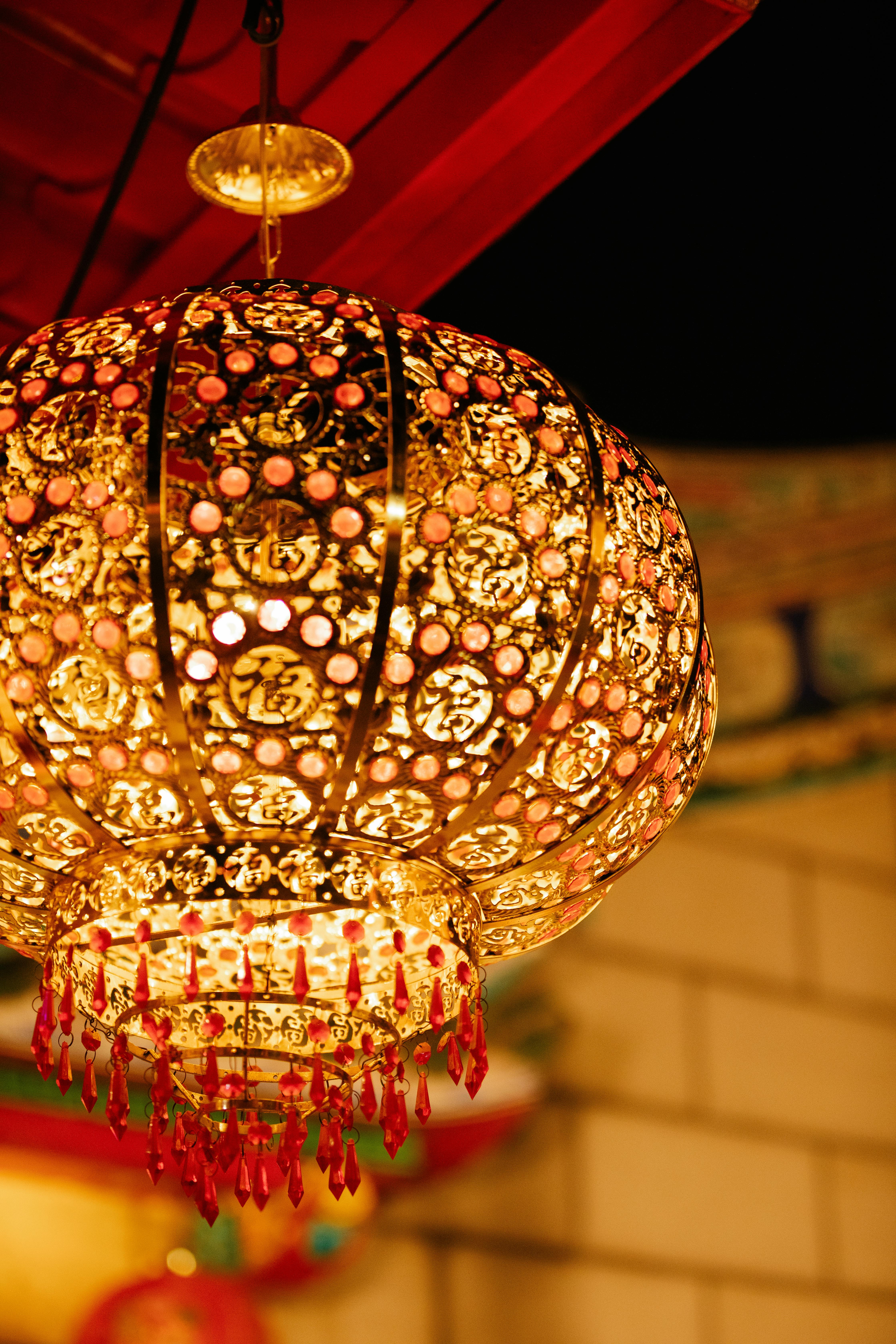 glowing carved metal lantern hanging on street at night during traditional festival