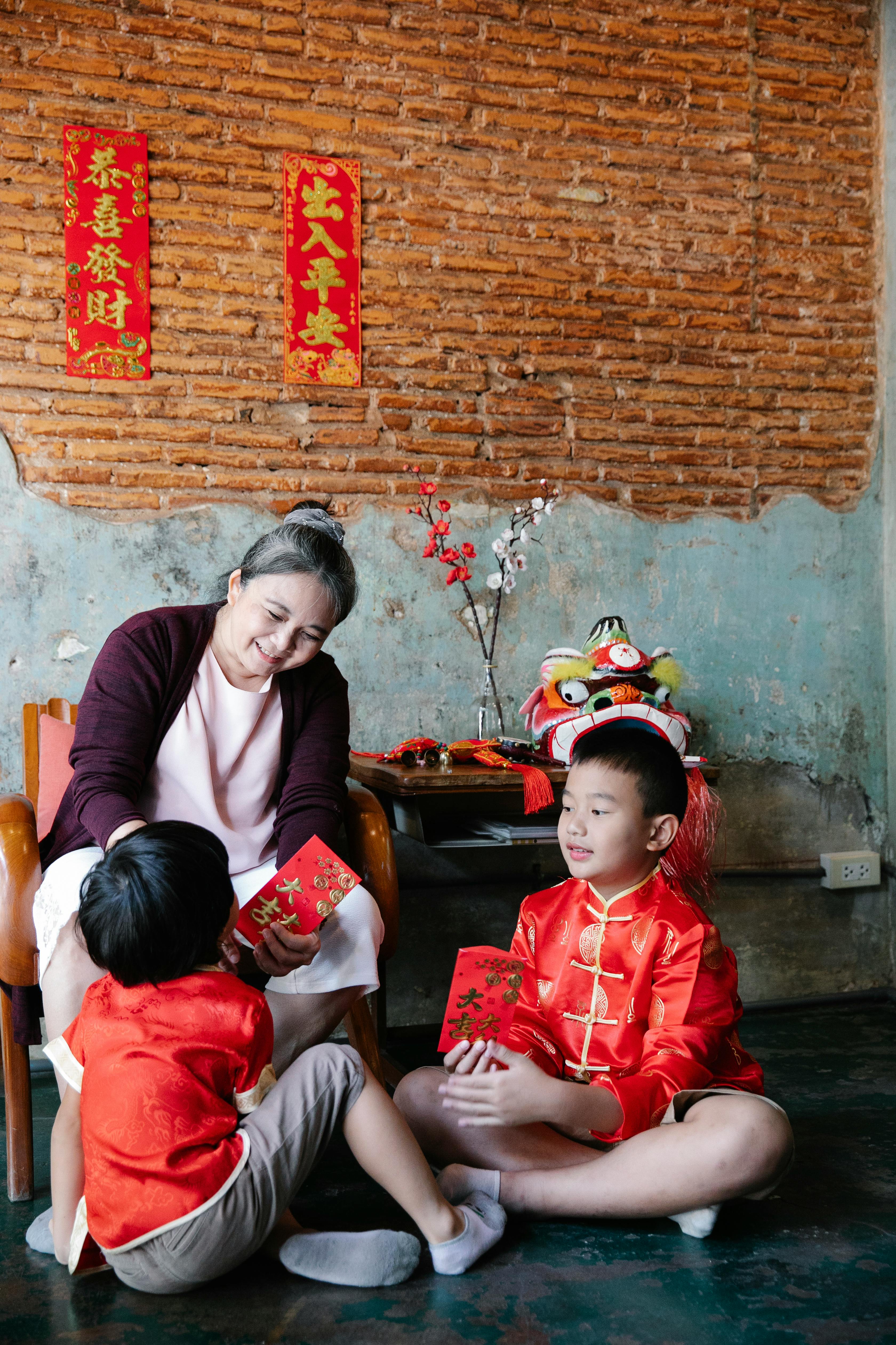 happy senior ethnic woman gifting red envelopes to grandsons during new year celebration