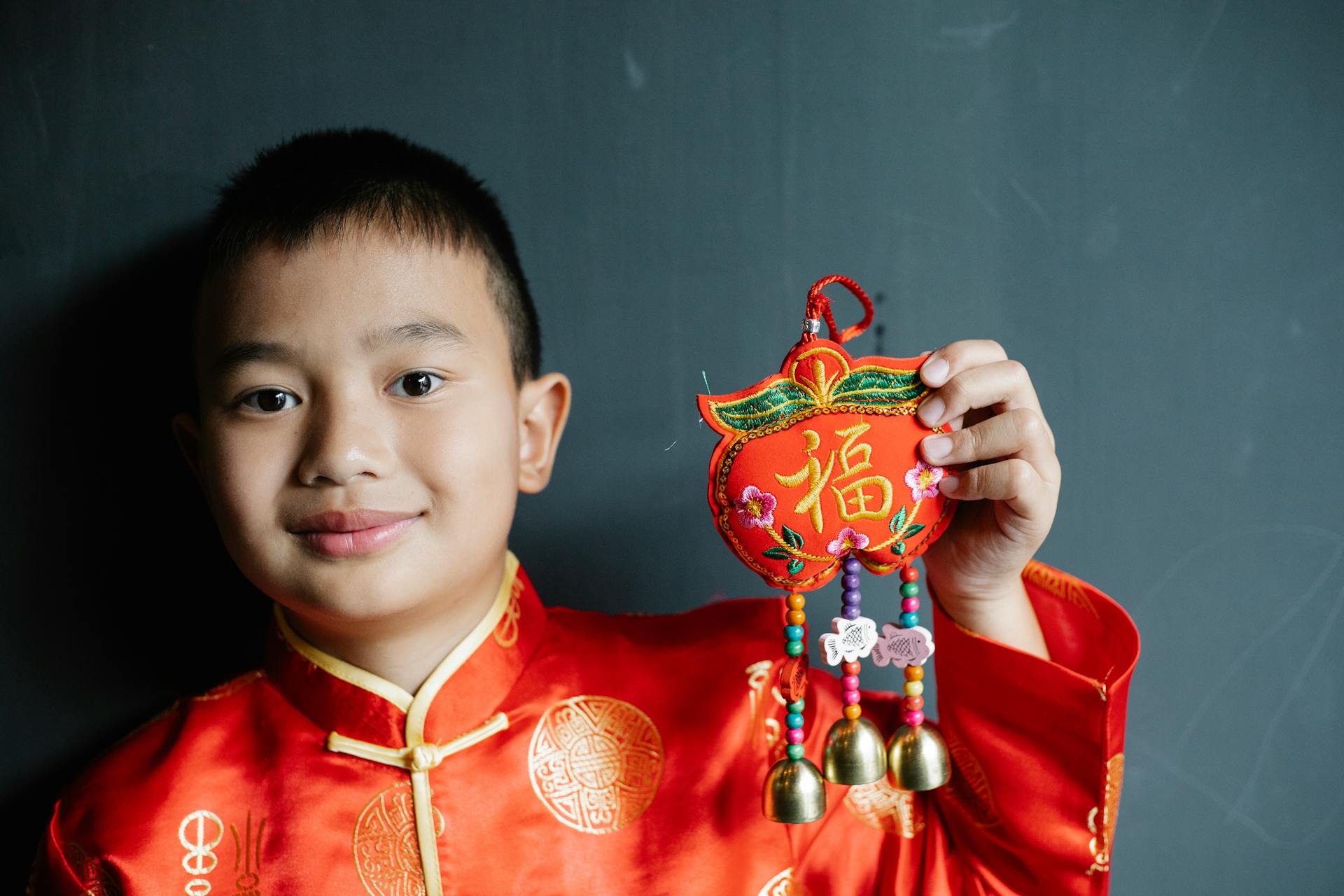 A joyful boy in traditional Chinese attire celebrates the New Year with festive decorations.