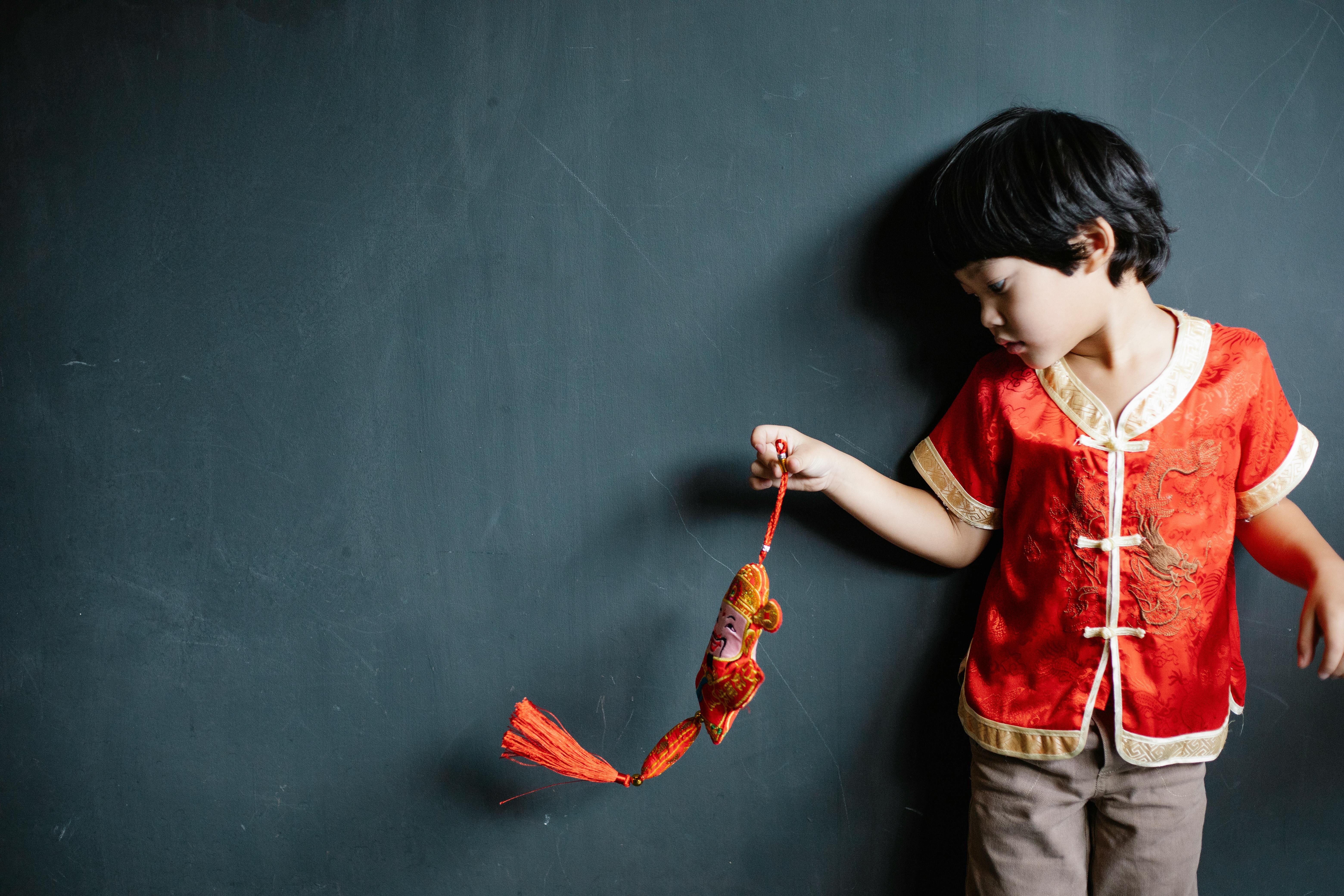 little boy in a traditional chinese shirt holding an ornament