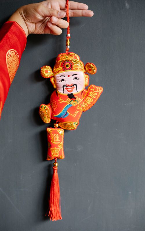 Free A festive Chinese New Year decoration held by a hand against a gray background. Stock Photo