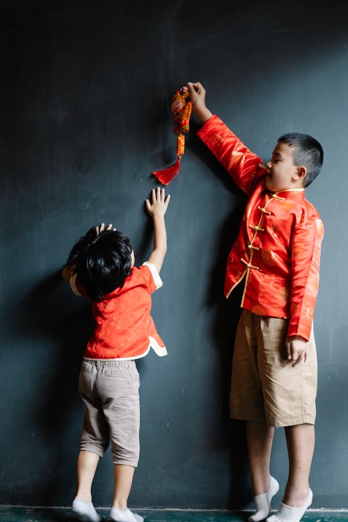 Boy Holding a Toy Up with his Sister Reaching for it 