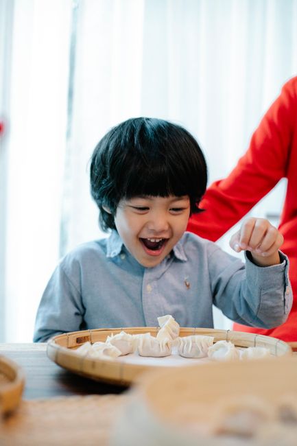 Joyful child engaging in dumpling preparation, showcasing happiness and cultural cuisine