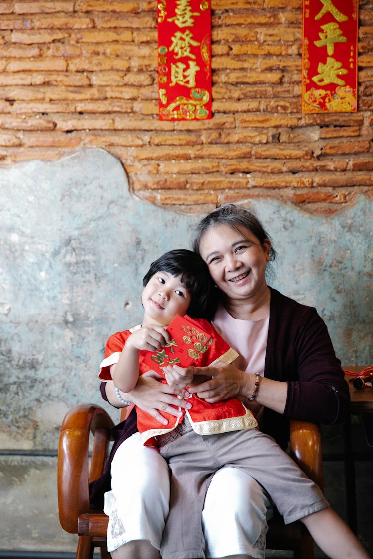 A Young Boy Sitting On The Lap Of His Grandmother