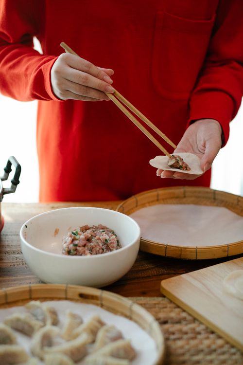 Free Hands preparing homemade dumplings with chopsticks, highlighting traditional cooking techniques. Stock Photo