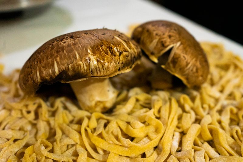 A close-up shot of fresh Portobello mushrooms sitting atop homemade pasta, perfect for gourmet cuisine.