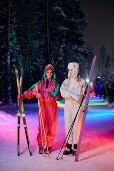 Two women in retro ski suits posing with skis on a colorful illuminated night trail.