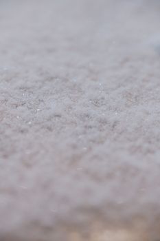 Macro shot of a frosty snow surface capturing the intricate texture of winter freeze.