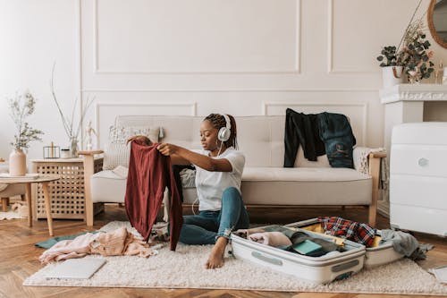 A Woman Listening on Her Headphones while Packing