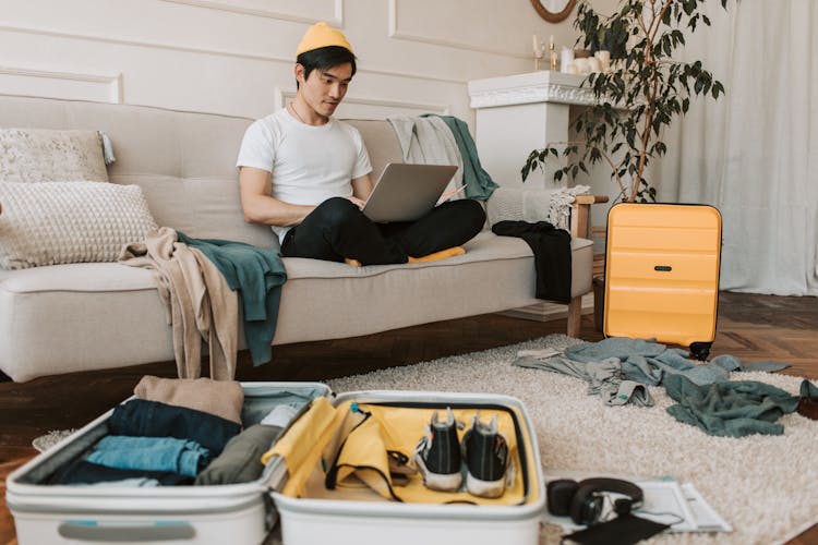 A Man Using His Laptop In A Messy Living Room