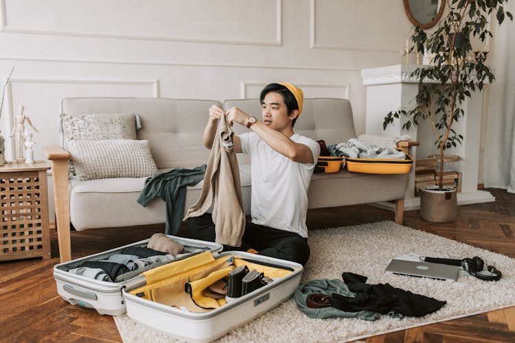 A Man Packing Clothes In A Suitcase