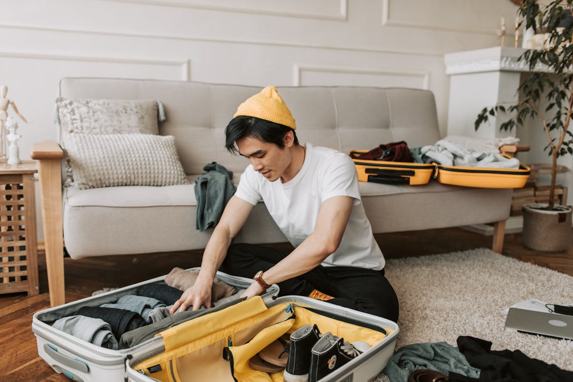 A Man Packing Clothes in Luggages