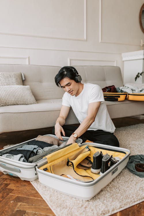 Free A Man Listening on His Headphones while Packing His Clothes Stock Photo