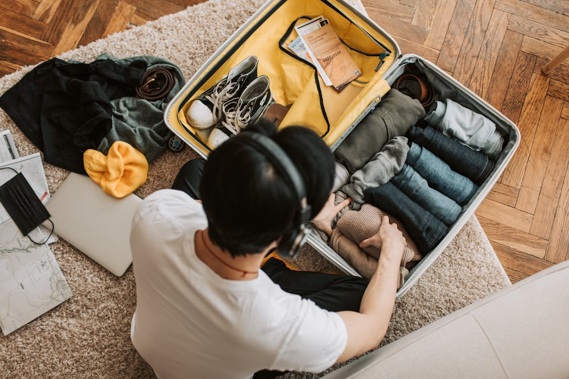 Free A Man Listening on His Headphones while Packing His Clothes Stock Photo