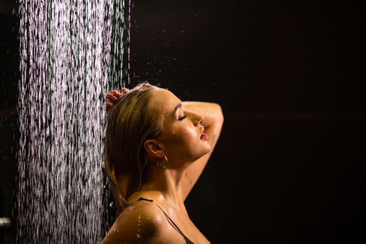 A woman enjoying a refreshing shower, captured beautifully in dim light, highlighting her contentment.