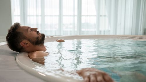 Free A serene moment of relaxation as a man enjoys a dip in an indoor pool, emphasizing self-care and tranquility. Stock Photo