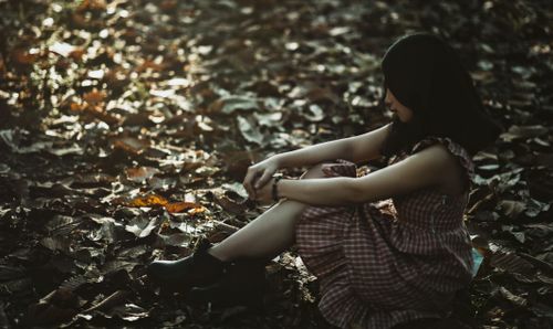 Free A thoughtful woman sitting among fallen autumn leaves, highlighting introspection. Stock Photo