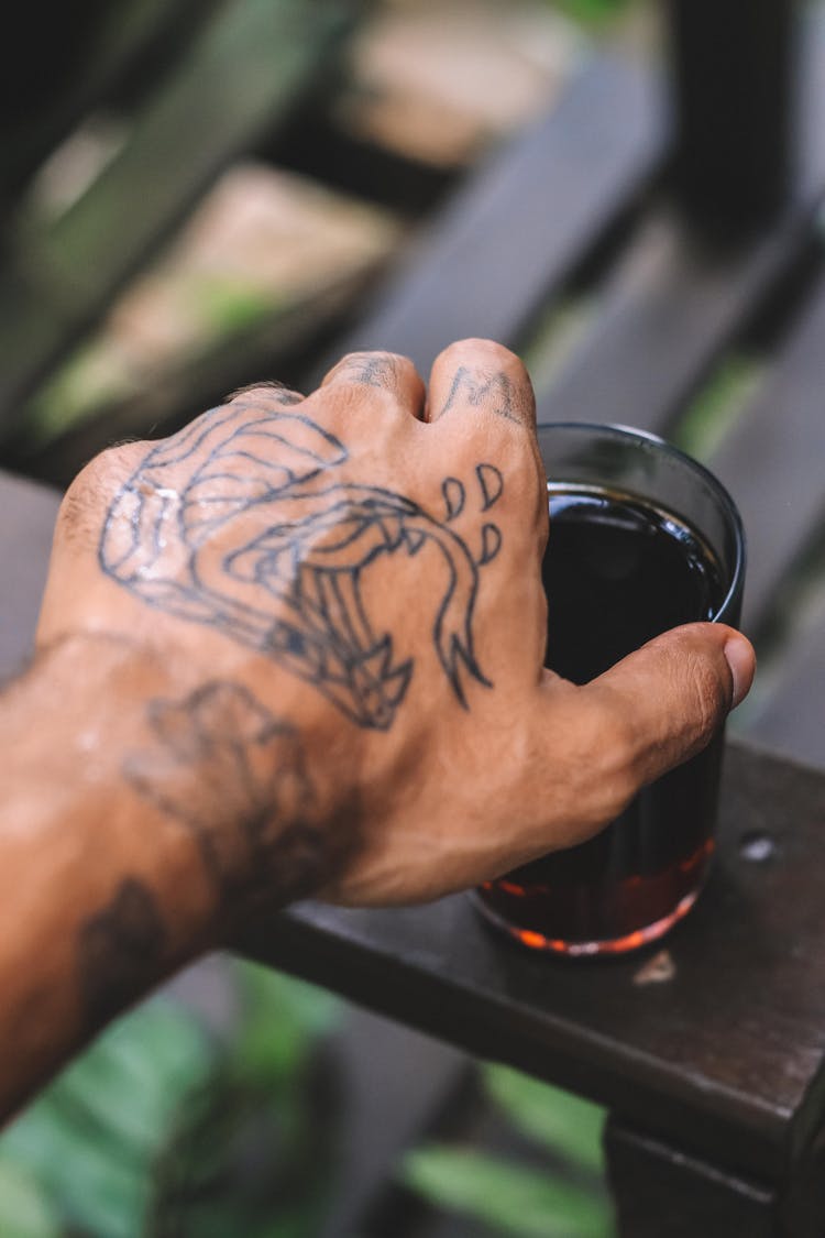 A Person Reaching For A Glass Of Drink