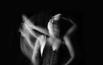 Black and white of melancholic young female in dress touching forehead and looking away thoughtfully