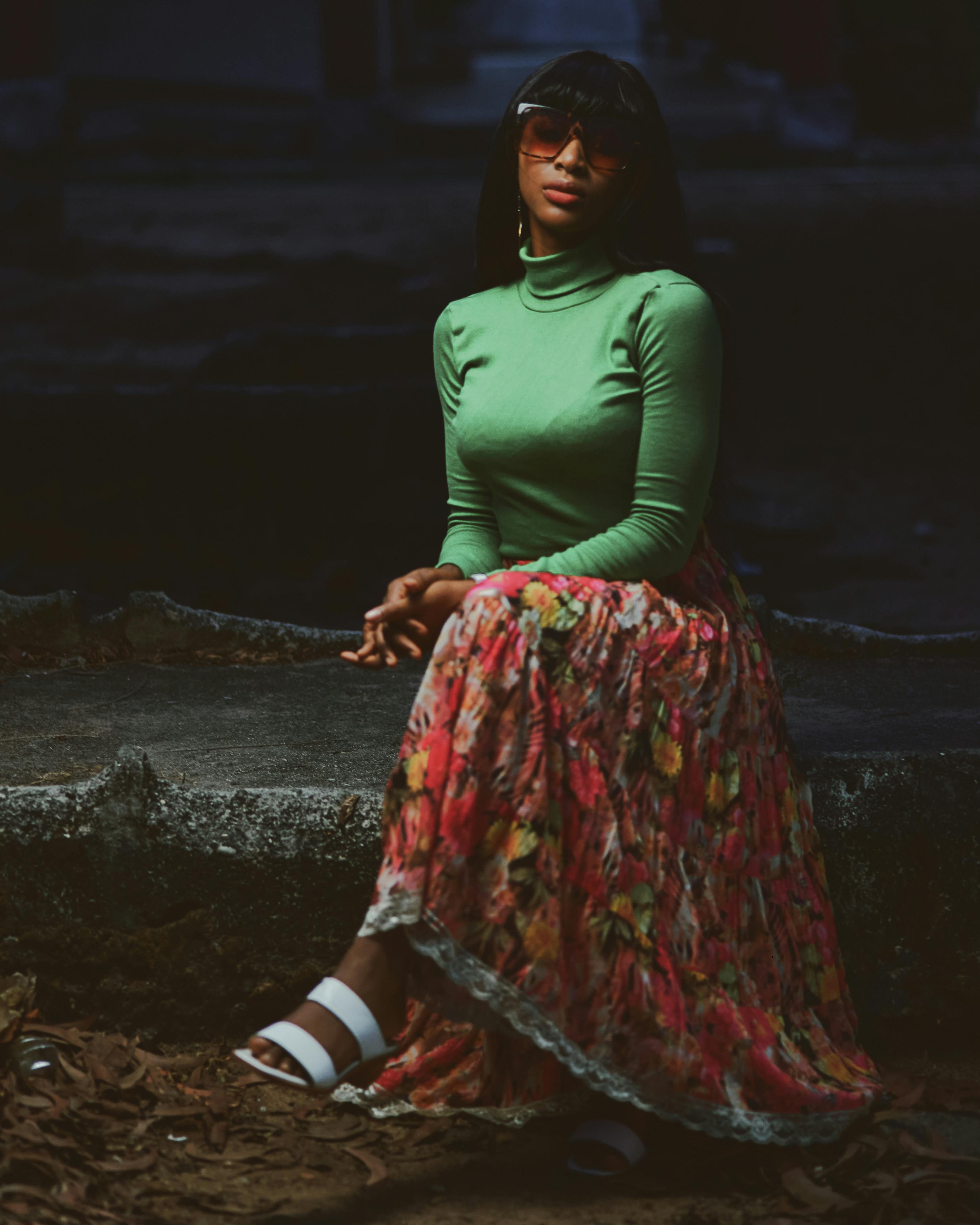 A Woman in Green Long Sleeves and Floral Skirt Sitting with Her Legs Crossed  · Free Stock Photo