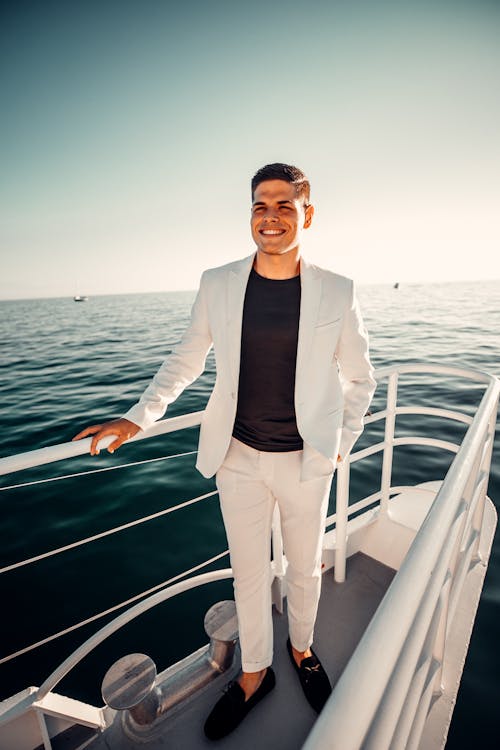 Elegant Man in a White Suit Standing on a Yacht 