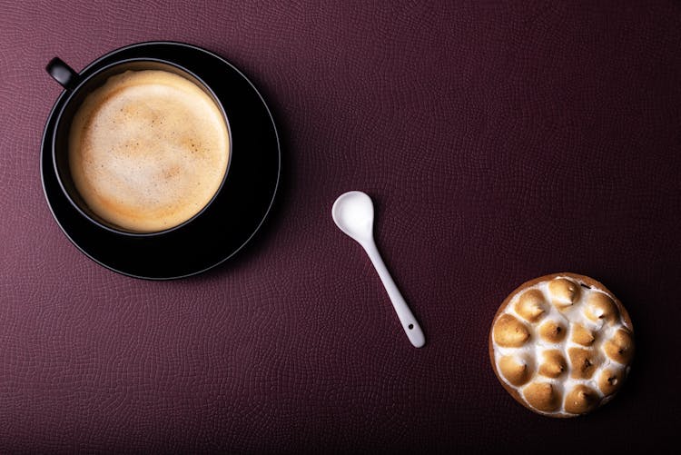 A Cup Of Coffee And Burnt Marshmallow On The Black Table Top