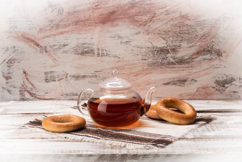 Free Glass teapot with black tea and bagels on rustic table setting. Perfect for cozy moments. Stock Photo