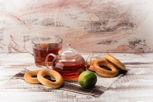 Free A warm tea setup with a teapot, cup, lime, and donuts on a wooden table. Stock Photo