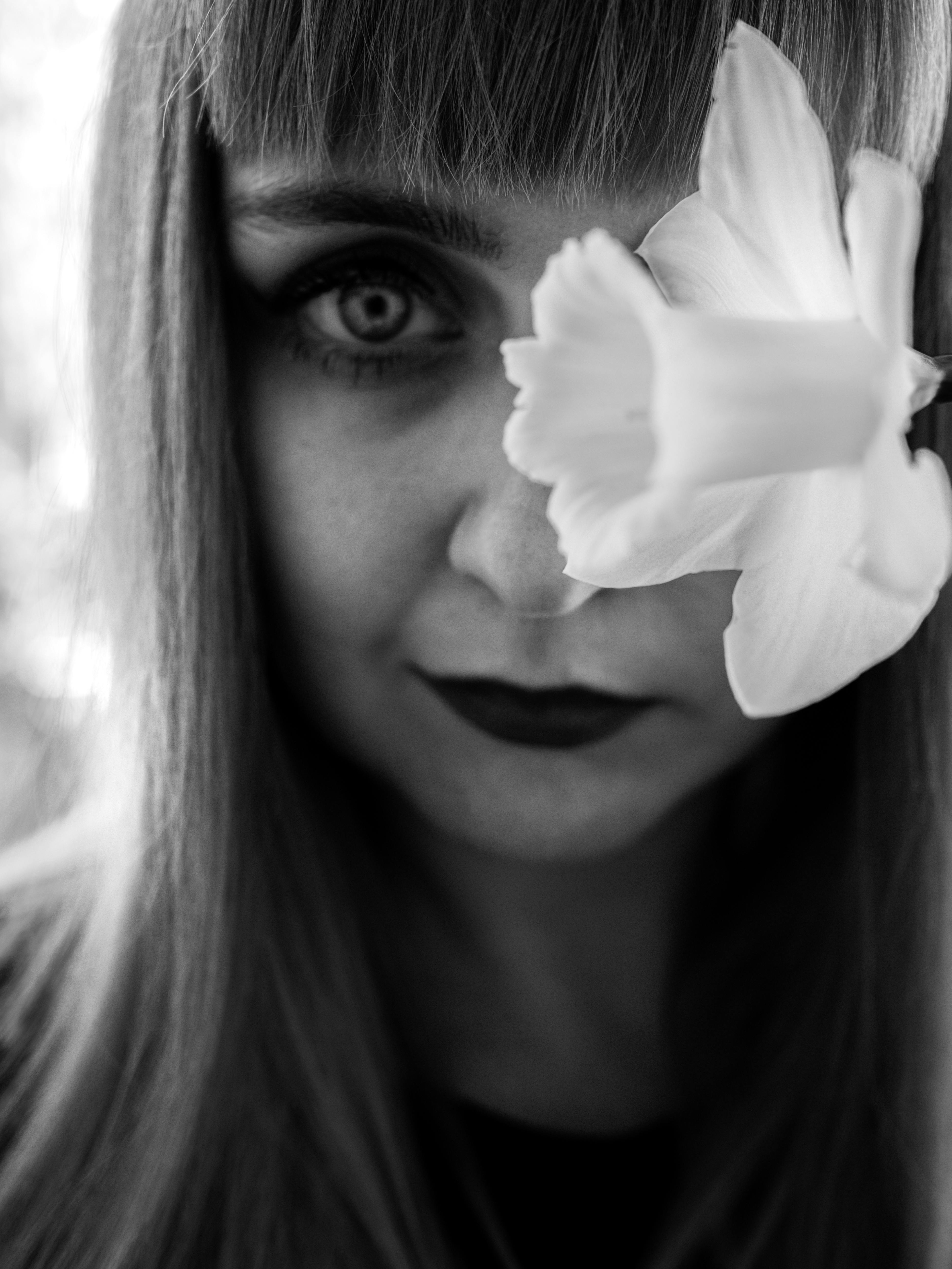 Black and white portrait of a woman with a flower in focus.