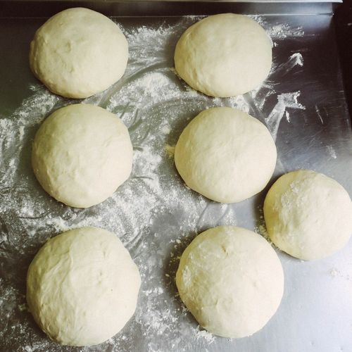 Free Seven fresh dough balls on a floured metal surface, prepared for baking. Stock Photo