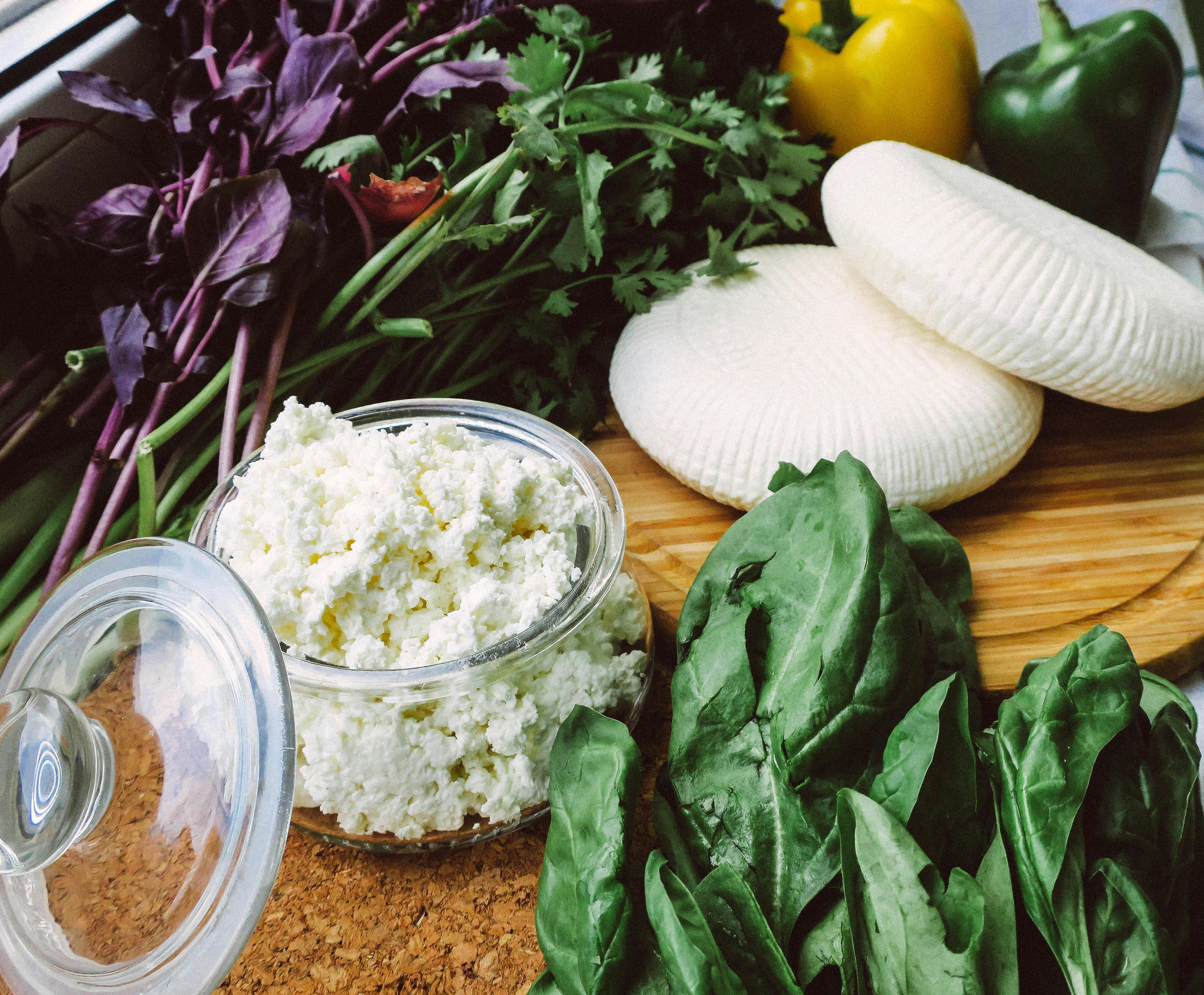 Close-up of fresh ricotta cheese, leafy greens, and bell peppers, perfect for salads and healthy recipes.