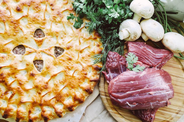 Raw Meat On A Cutting Board, A Pie And Mushrooms 