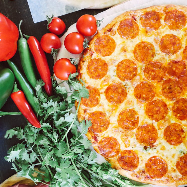 Top View Of Pizza With Salami With Green And Red Raw Vegetables