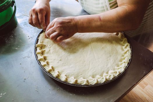Hands shaping pie dough on a baking tray, showcasing homemade food preparation.