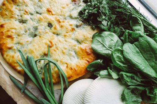 Free Delicious cheese pie accompanied by fresh herbs and slices of ricotta cheese. Stock Photo