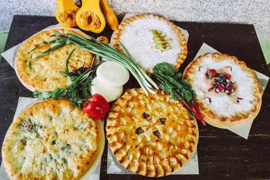 A high-angle view of various pies with fresh vegetables, showcasing a mix of savory and sweet flavors.