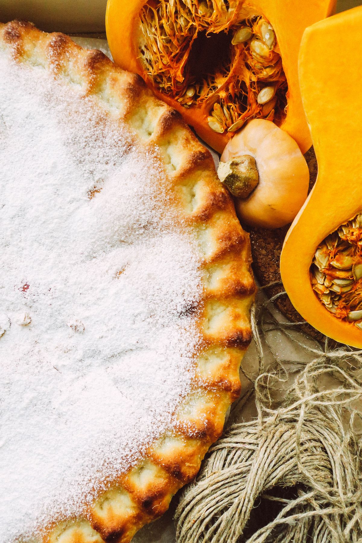 Freshly baked pumpkin pie with powdered sugar and sliced pumpkins