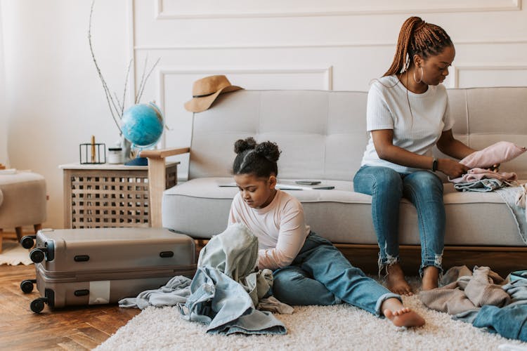 Mother And Daughter Sitting While Folding Clothes