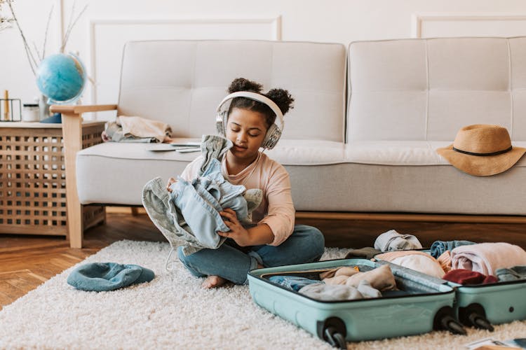 Kid With Headphones Packing Her Clothes