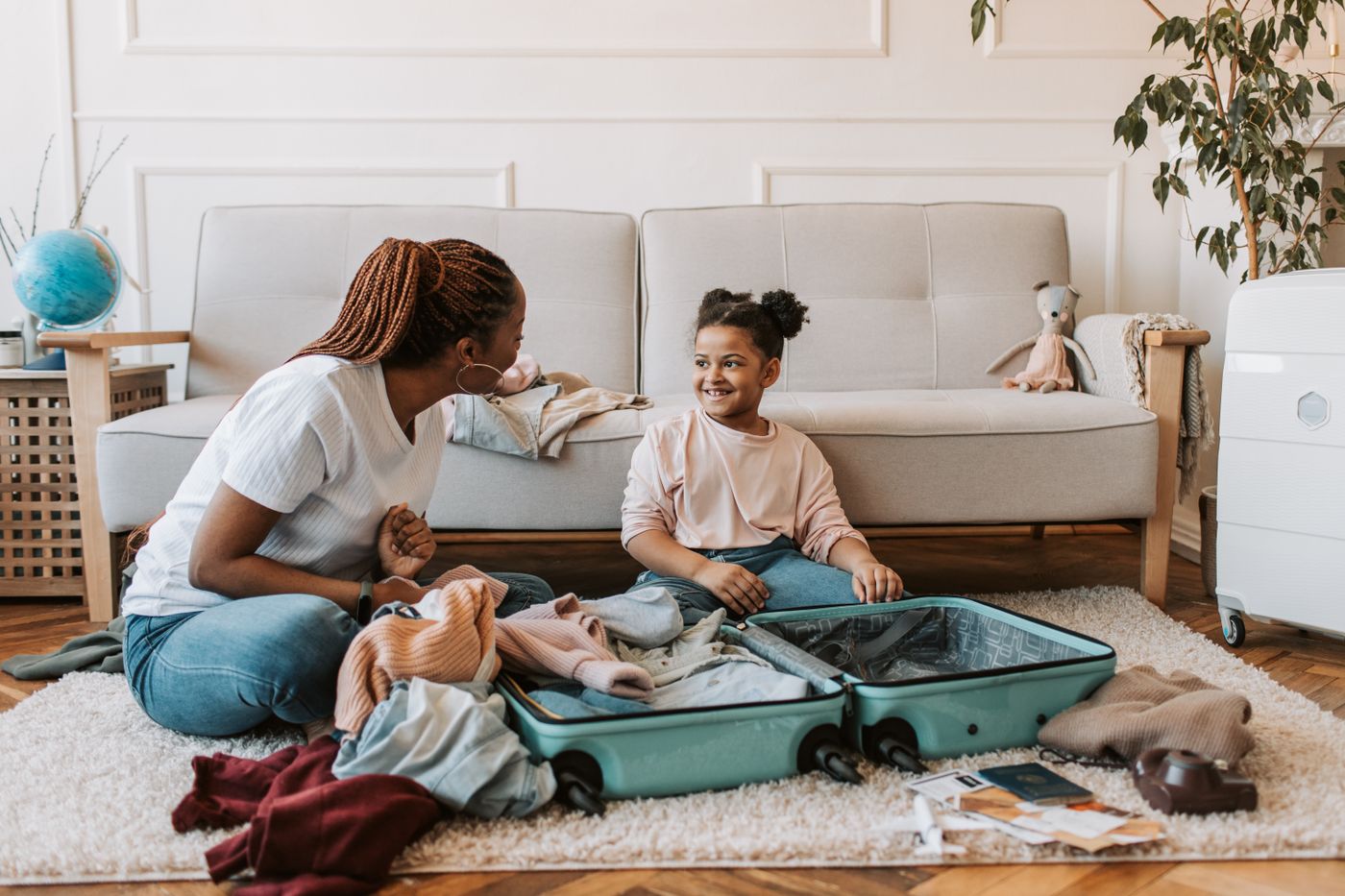 Mother and daughter packing clothes together into a suitcase