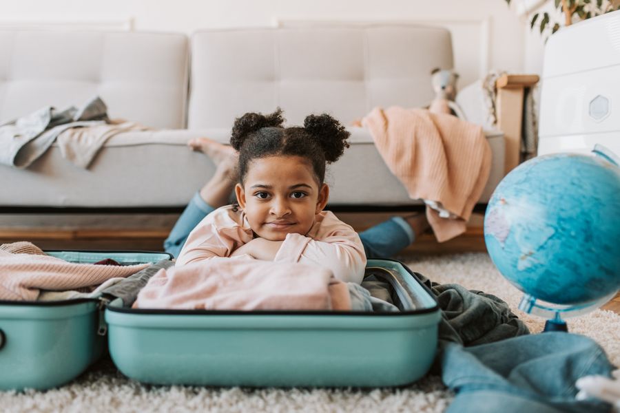 Cute child enjoying playful moments in a suitcase on the floor indoors.