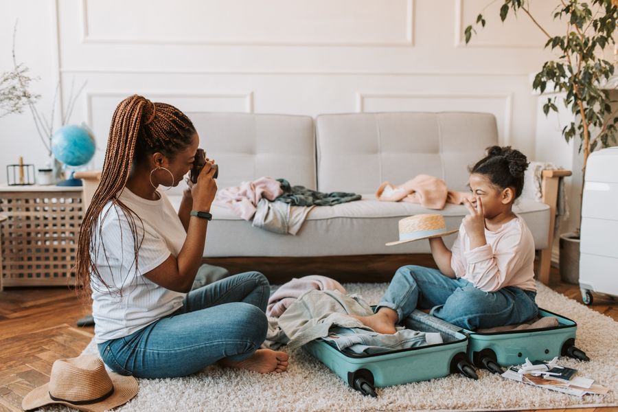 Heartwarming photo of mother and daughter taking pictures and packing indoors.