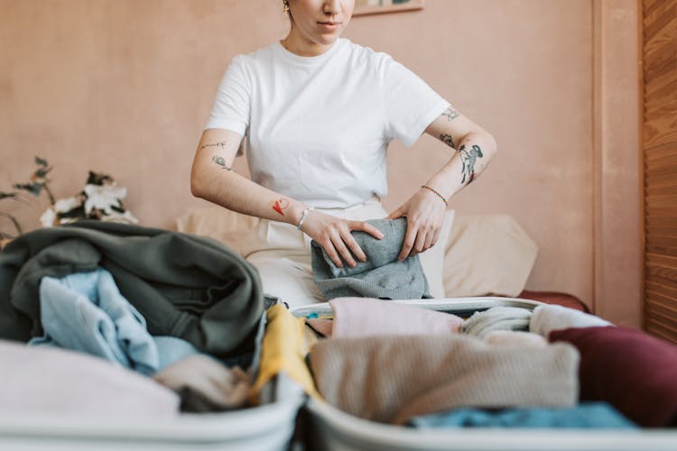 Woman In White T-shirt Folding Her Clothes